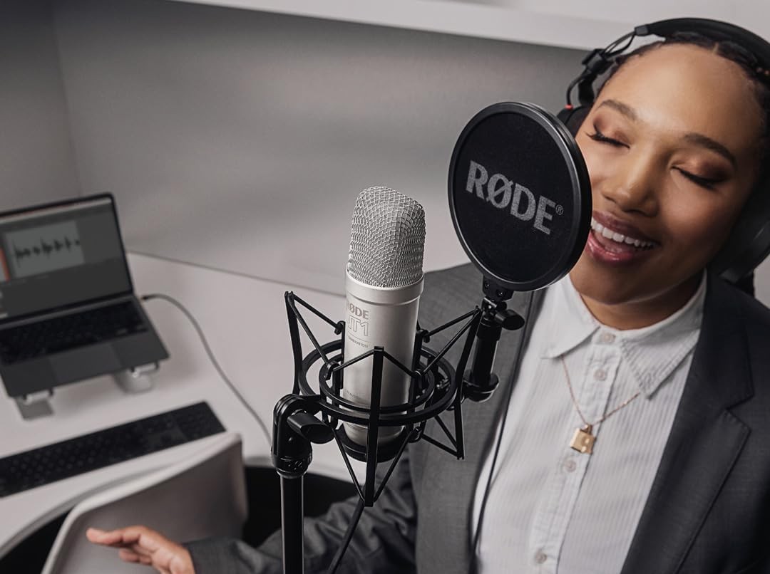 Person in headphones recording in studio with RØDE microphone, laptop visible in background