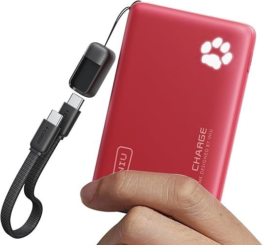 Red portable power bank with paw print design and USB-C cable in hand for charging devices